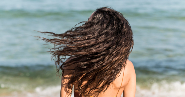 Devojka sa kovrdžavom kosom stoji na plaži